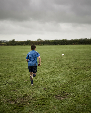 Player chasing a stray football across an open field